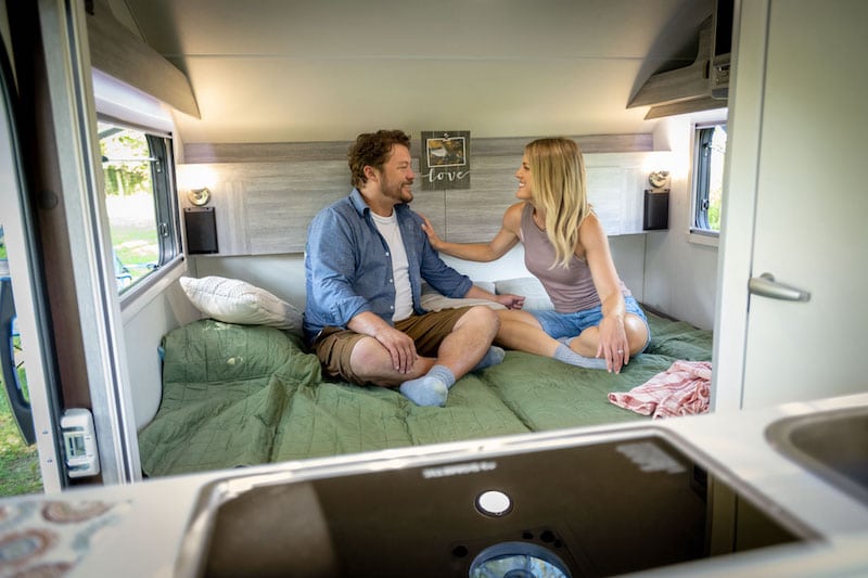 couple on bed inside their ultimate camper