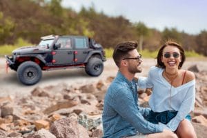 couple sitting in front of Jeep on beach